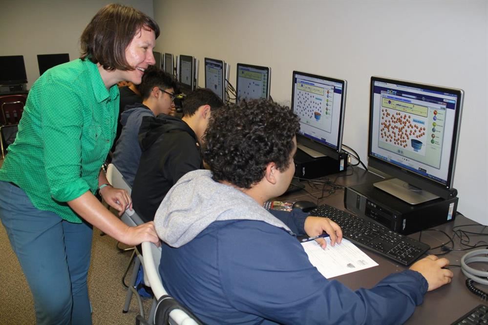 teacher working with three boys on the computer