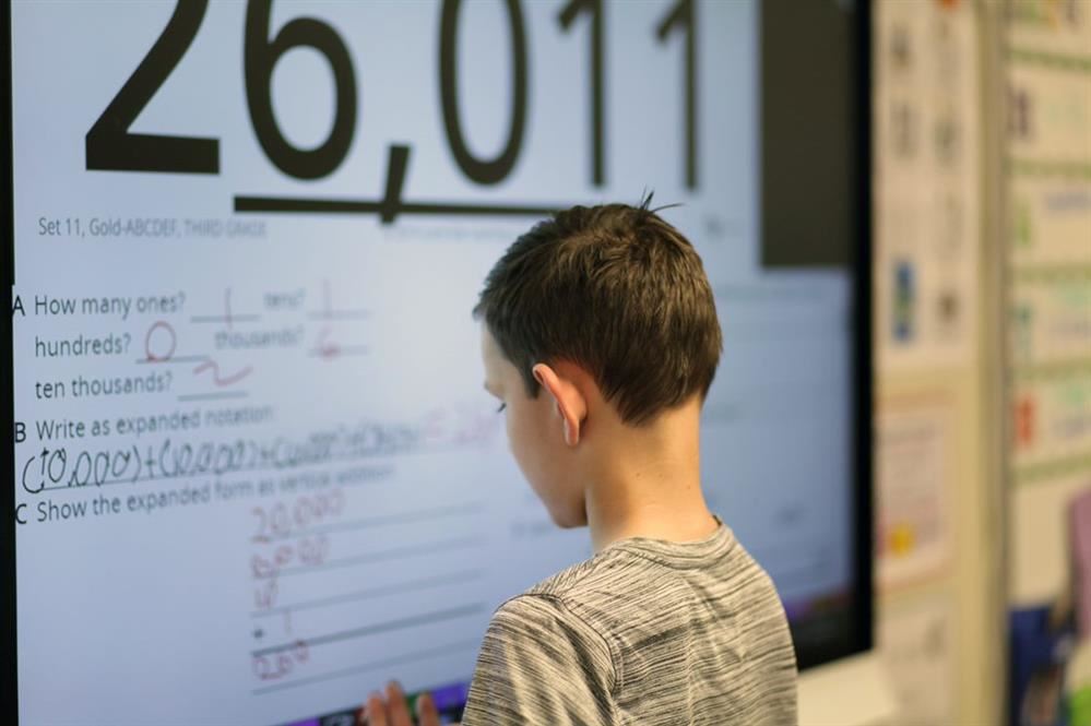 Student working a math problem on a white board